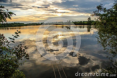 Fishing adventures, carp fishing. Angler, at sunset, is fishing with carpfishing technique. Camping on the shore of the lake.Carp Stock Photo