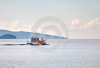 Fishing boat carrying two fisherman sailing over the calm sea in winter time in Gumusluk, Bodrum, Turkey Editorial Stock Photo