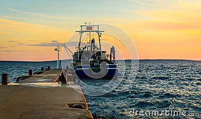 Fishing boat moored or docked at pier in sunset Stock Photo