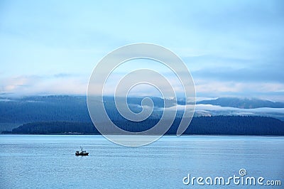 Fishing Boat with Mountains and Low Clouds Stock Photo