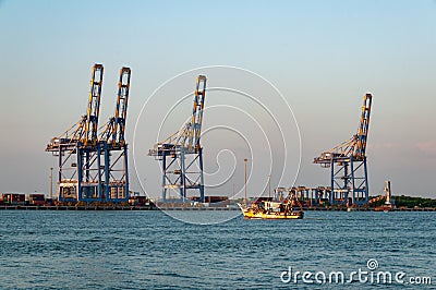 Fishing boat puts out to sea from Cochi port, with heavy industry in the background Editorial Stock Photo