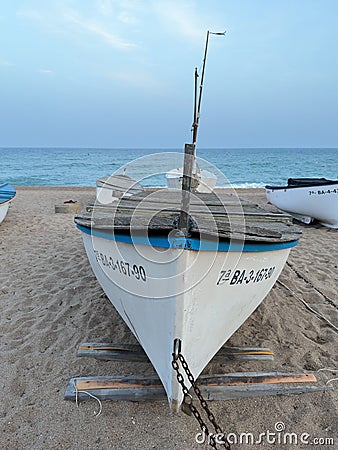 Fishing boat on sandy beach at sunset in Pineda de Mar, Spain Editorial Stock Photo