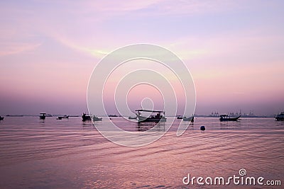 Fishing boat silhouette with orange sunrise sky and water reflection Stock Photo