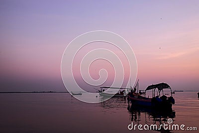 Fishing boat silhouette with orange sunrise sky and water reflection Editorial Stock Photo