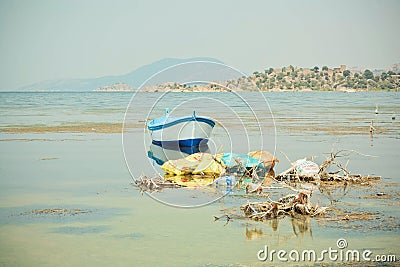 Fishing boat on the water of drying lake Bafa with pollution by garbage Stock Photo