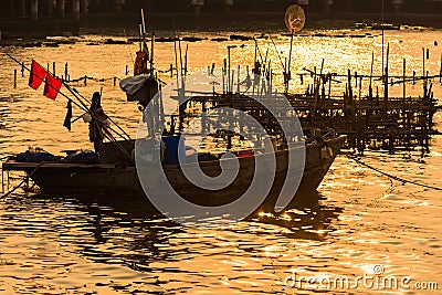 Fishing boats floating in the golden sea at sunset Stock Photo