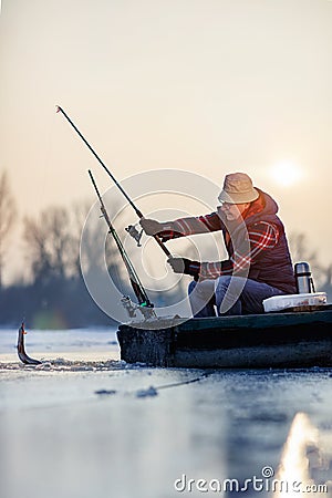 Fishing on frozen lake- Happy fisherman catch fish Stock Photo