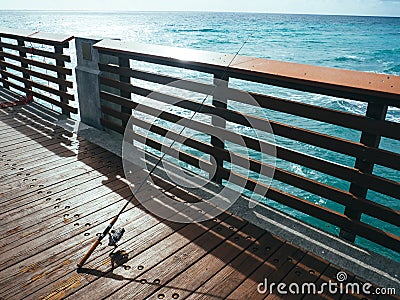 Fishing Pole on Pier on Ocean Stock Photo