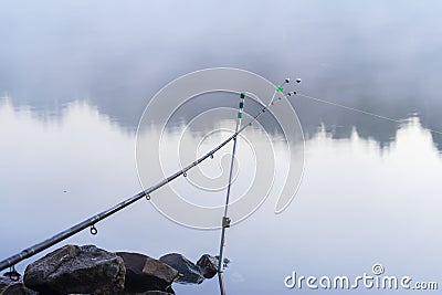 Fishing rod on the bank, quiet early morning on lake, dawn, first rays of the sun. Seasons, environment, natural beauty Stock Photo