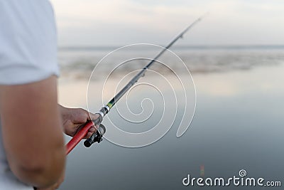 Fishing rod with a float in male hands. The man is a fisherman. River or estuary. Modern fishing tackle. I& x27;m waiting for Stock Photo