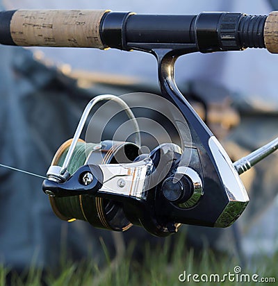 Fishing rod and reel for catching fish close-up on a blurry background. Inertia-free reel and fishing line. Stock Photo