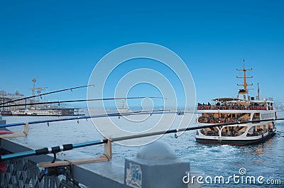 Fishing rods in Istanbul EminÃ¶nÃ¼ and a ferry that took its way from the harbor. Stock Photo