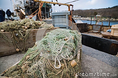 Fishing tackle and nets for trawling fishing are in the port docklie on the background of the ship Stock Photo