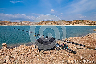 Fishing tackles lie on a shore of lake. Stock Photo