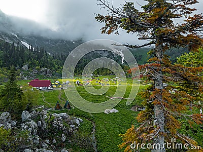 The fisht shelter is illuminated by a sunbeam in cloudy weather. Tourist camp filled with tents, top view. Tourist route no. 30 Stock Photo