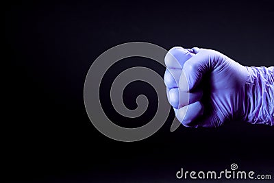 Fist of right man hand in a purple medical glove on a black background Stock Photo