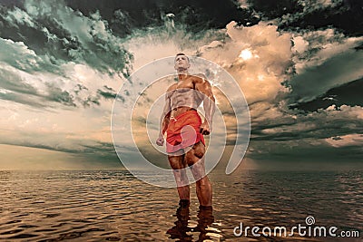 Fit athlete bodybuilder in the sea. Attractive young man lifeguard. Stock Photo