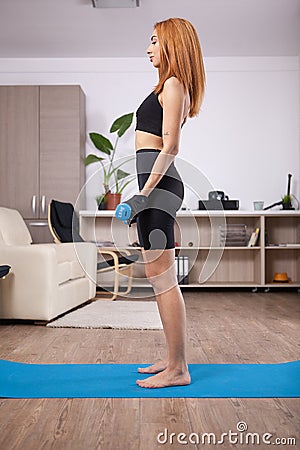 Fit blonde girl doing lateral biceps curls in her home training progam Stock Photo
