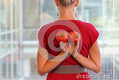 Fit business woman with tomatoes as a healhy snack - back view Stock Photo