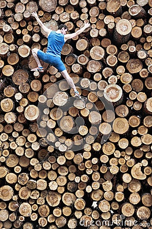Fit climber going down the large pile of cut wooden logs Stock Photo