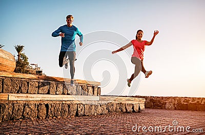 Fit couple doing workout running session at sunset outdoor - Sporty young people jogging next the beach Stock Photo