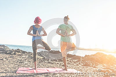 Fit couple doing yoga outdoor on the beach at sunset - Woman and man training on evening time - Tilted horizon composition - Soft Stock Photo