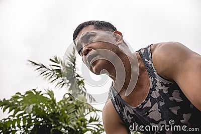 A fit and determined 50 year old asian man in a tank top and an intense ruthless look during a workout. Stock Photo