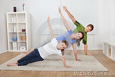 Fit family doing side plank yoga at home Stock Photo