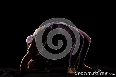 Fit girl practicing yoga in a studio. Half silhouette side lit fitness model Stock Photo