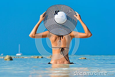 Fit girl on a tropical beach with hat. Sexy bikini body woman on paradise tropical beach. Beautiful fit body girl on Stock Photo