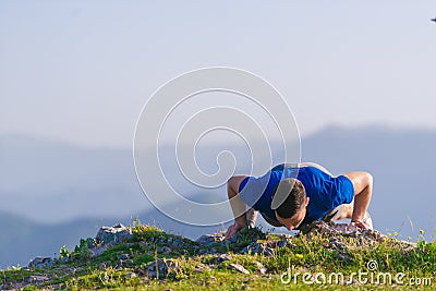 Fit male athlete doing push ups at the edge of a cliff while enjoying the amazing view Stock Photo