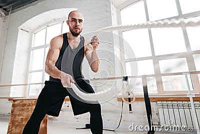 Fit man athlete using battle ropes for exercising at light sport hall Stock Photo