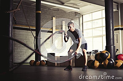 Man with battle ropes in gym Stock Photo