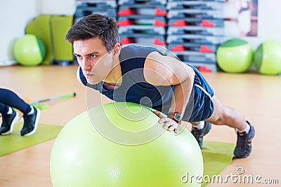 Fit man exercising with fit ball workout out arms Exercise training triceps and biceps doing push ups. Stock Photo