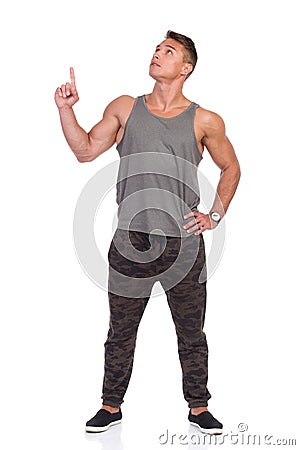 Fit Man In Gray Tank Top And Camo Pants Looking Up And Pointing Stock Photo