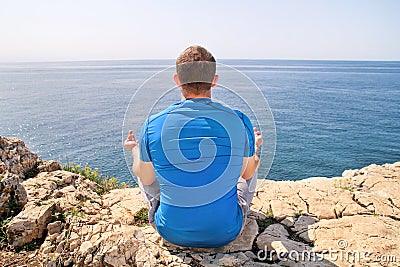 A fit man in the Lotus position on a seashore. Young fitness man doing yoga outdoors. Stock Photo