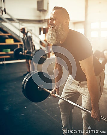 Fit mature man straining to lift weights in a gym Stock Photo