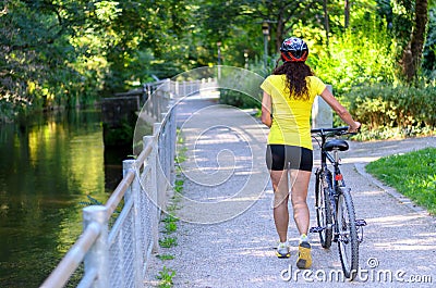 Fit muscular woman wheeling her bicycle outdoors Stock Photo
