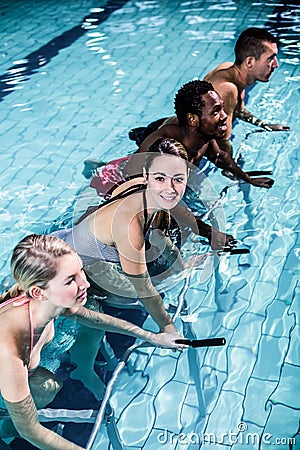 Fit smiling group pedaling on swimming bike Stock Photo