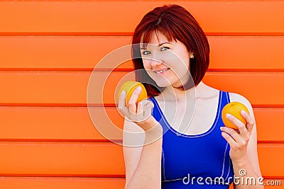 Fit smiling young woman with two oranges against colored wall. Freshness, woman health and wellness concept. Room for text Stock Photo