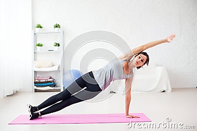 Fit woman doing side plank yoga pose at home in Stock Photo