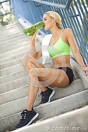 Fit woman drinking sports bottle on steps Stock Photo