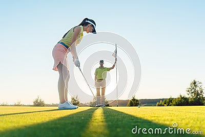 Fit woman exercising hitting technique during golf class Stock Photo