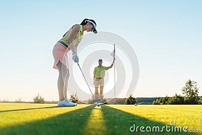 Fit woman exercising hitting technique during golf class with an Stock Photo