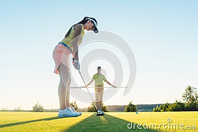 Fit woman exercising hitting technique during golf class with Stock Photo