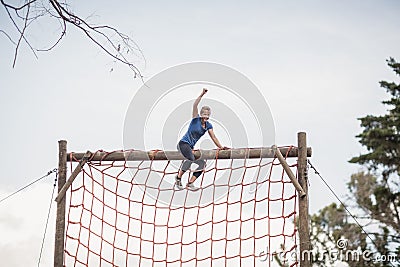 Fit woman with hand raised celebrating success during obstacle course Stock Photo