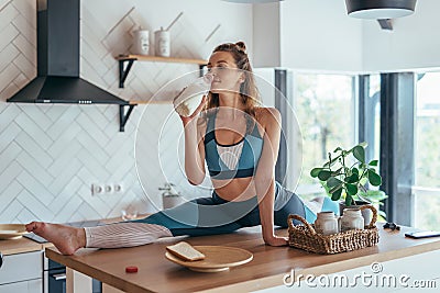 Fit woman having breakfast in split position on the kitchen table. Stock Photo
