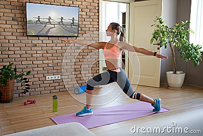 Fit woman learning yoga pose watching streaming online workout on tv at home. Stock Photo