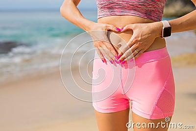 Fit woman showing hands heart sign on her stomach Stock Photo
