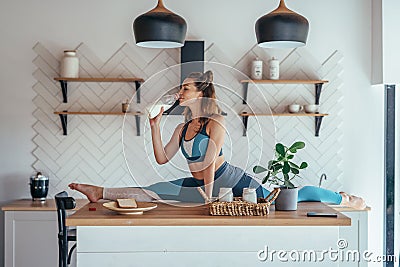 Fit woman in split position on the kitchen table having breakfast. Stock Photo